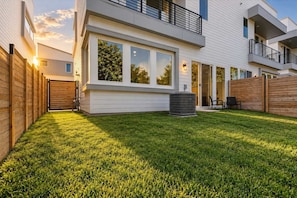 A modern two-story house with a well-maintained lawn, a large window, and a visible air conditioning unit. - Regent Sol - Scandinavian Luxury - Central Austin (Austin)