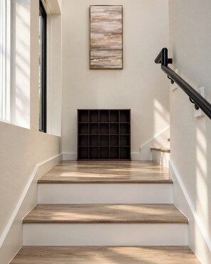 A staircase with wooden steps and a black metal handrail, leading to a landing with a black grid-like structure. - Regent Sol - Scandinavian Luxury - Central Austin (Austin)