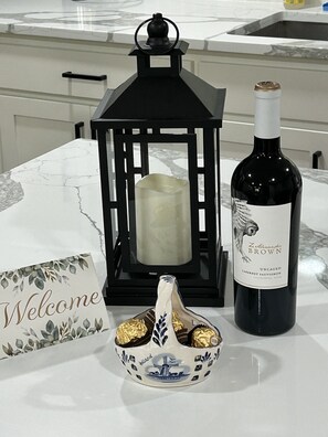 Een tafel met een fles wijn, een kaars en een decoratieve schaal.