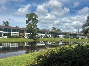 Ein Gebäude mit einem spiegelnden Teich davor, umgeben von Grünflächen und Bäumen.