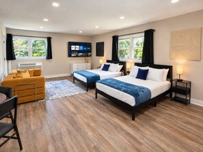 A hotel room with two beds, a sofa, a TV, and a desk. - Furnished Studio | 2 Full Beds | Short & Mid-Stay (Crystal Lake)