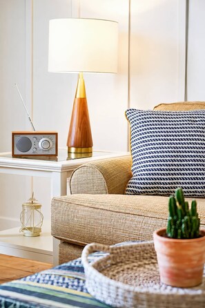 A cozy living room with a wooden radio, a lamp, a patterned pillow, a woven basket, and a potted plant. - The Newport | Pool • Hot Tub • Lake • Free Golf (Holland)