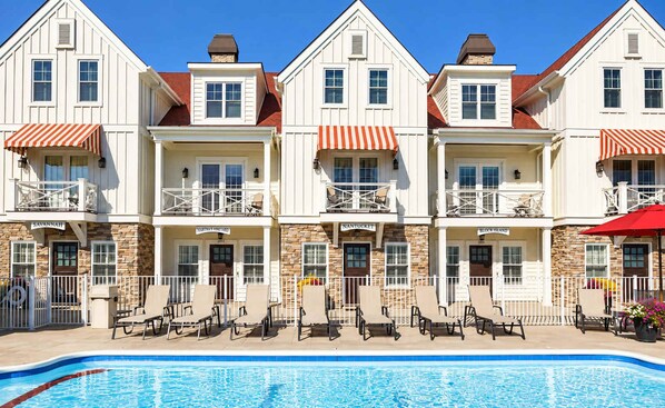Un hotel con piscina, varios balcones y zonas de estar al aire libre.