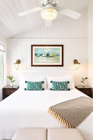 A bedroom with a bed, white walls, a ceiling fan, a framed painting, and two bedside lamps. - The Newport | Pool • Hot Tub • Lake • Free Golf (Holland)