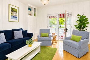 A living room with a blue sofa, striped armchairs, a white coffee table, and a green rug. - The Charleston | Pool • Hot Tub • Lake • Free Golf (Holland)