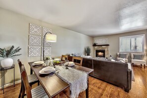 A dining area with a wooden table set for four, a fireplace, and a seating area with a sofa and chairs. - Lake Tahoe 2BR condo with pool, hot tub, lake views, and ski access Mv71 (Stateline)