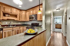 A kitchen with wooden cabinets, a stainless steel microwave, a stove, and a bowl of lemons on the counter. - Lake Tahoe 2BR condo with pool, hot tub, lake views, and ski access Mv71 (Stateline)