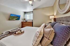 A bedroom with a bed, a ceiling fan, a mounted TV, a dresser, and a window with curtains. - Lake Tahoe 2BR condo with pool, hot tub, lake views, and ski access Mv71 (Stateline)