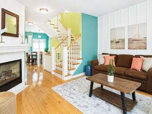 Ein Wohnzimmer mit Kamin, Treppe, einem braunen Sofa und einem Couchtisch.