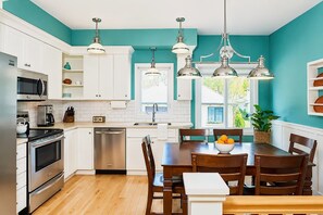 Een moderne keuken met witte kasten, roestvrijstalen apparatuur en teal muren.