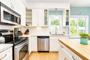A modern kitchen with white cabinetry, stainless steel appliances, and a wooden countertop. - The Hampton | Pool • Hot Tub • Lake • Free Golf (Holland)