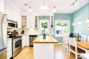 A modern kitchen with white cabinetry, stainless steel appliances, a wooden island, and pendant lighting. - The Hampton | Pool • Hot Tub • Lake • Free Golf (Holland)