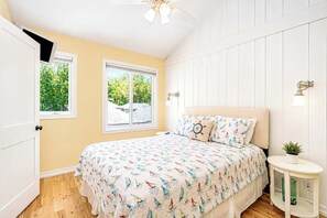 A bedroom with a bed, two windows, a ceiling fan, a nightstand, and a wall-mounted lamp. - The Hampton | Pool • Hot Tub • Lake • Free Golf (Holland)