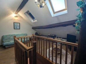 Une pièce de style loft avec un escalier en bois, une lucarne, un canapé et une petite table.