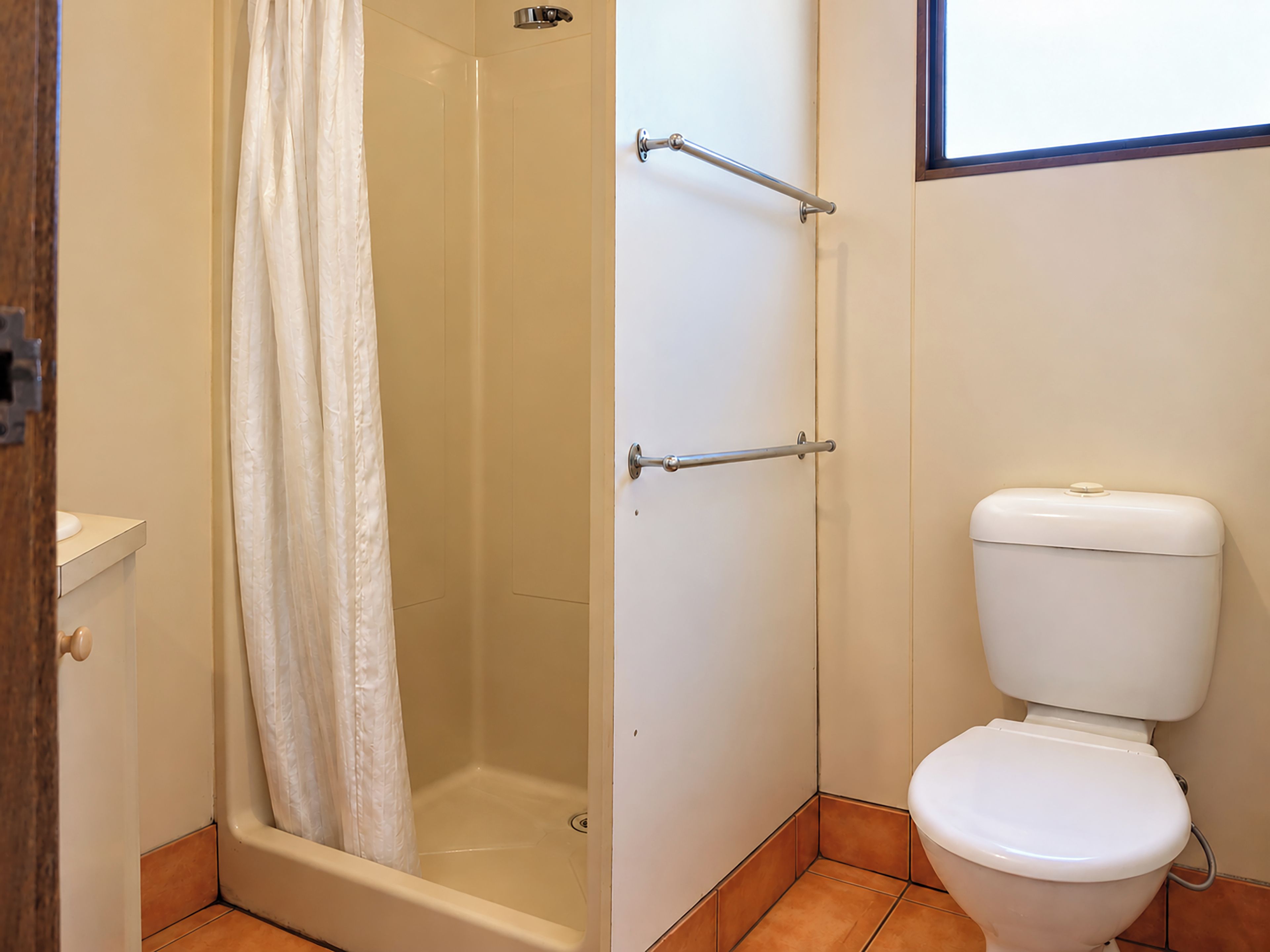 Ein Badezimmer mit Dusche, Toilette und einer Tür mit Handtuchhalter.