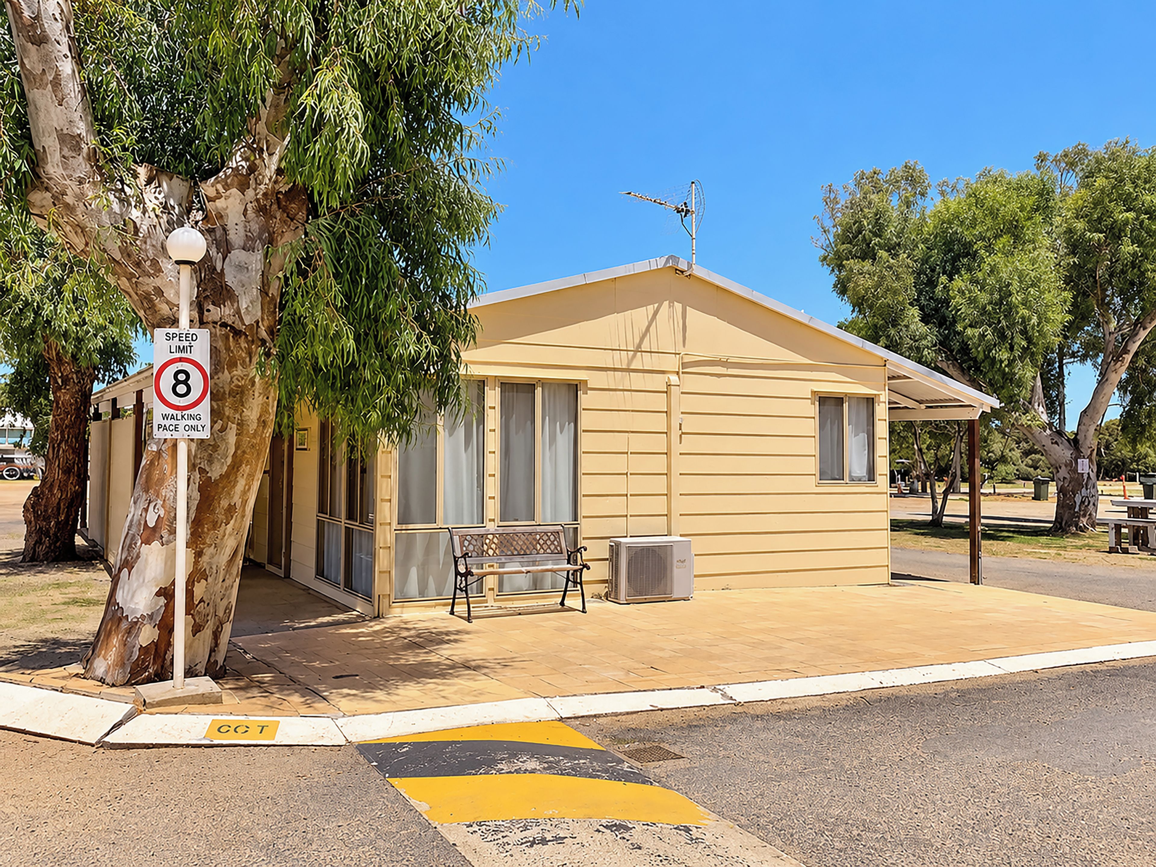 A small building with a speed limit sign, a bench, and a trash can.
