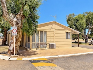 A small building with a speed limit sign, a bench, and a trash can.