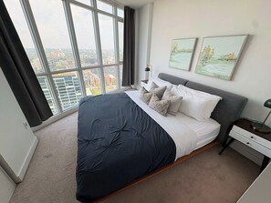 A modern bedroom with a large bed, a nightstand, a lamp, and two paintings on the wall. - Modern Core 1BR Oasis Walk to Rogers Centre! (Toronto)