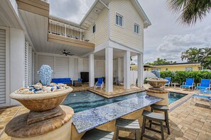 Ein zweistöckiges Haus mit Poolanlage, einschließlich einer Lounge mit Stühlen und einem Tisch.