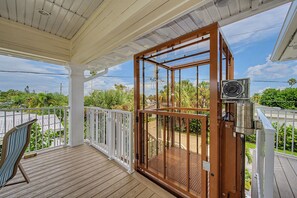 A covered outdoor area with a wooden deck, a glass door leading to a garden, and a ceiling fan. - New Remodel/Short Walk To Clearwater Beach/Pool (Clearwater)