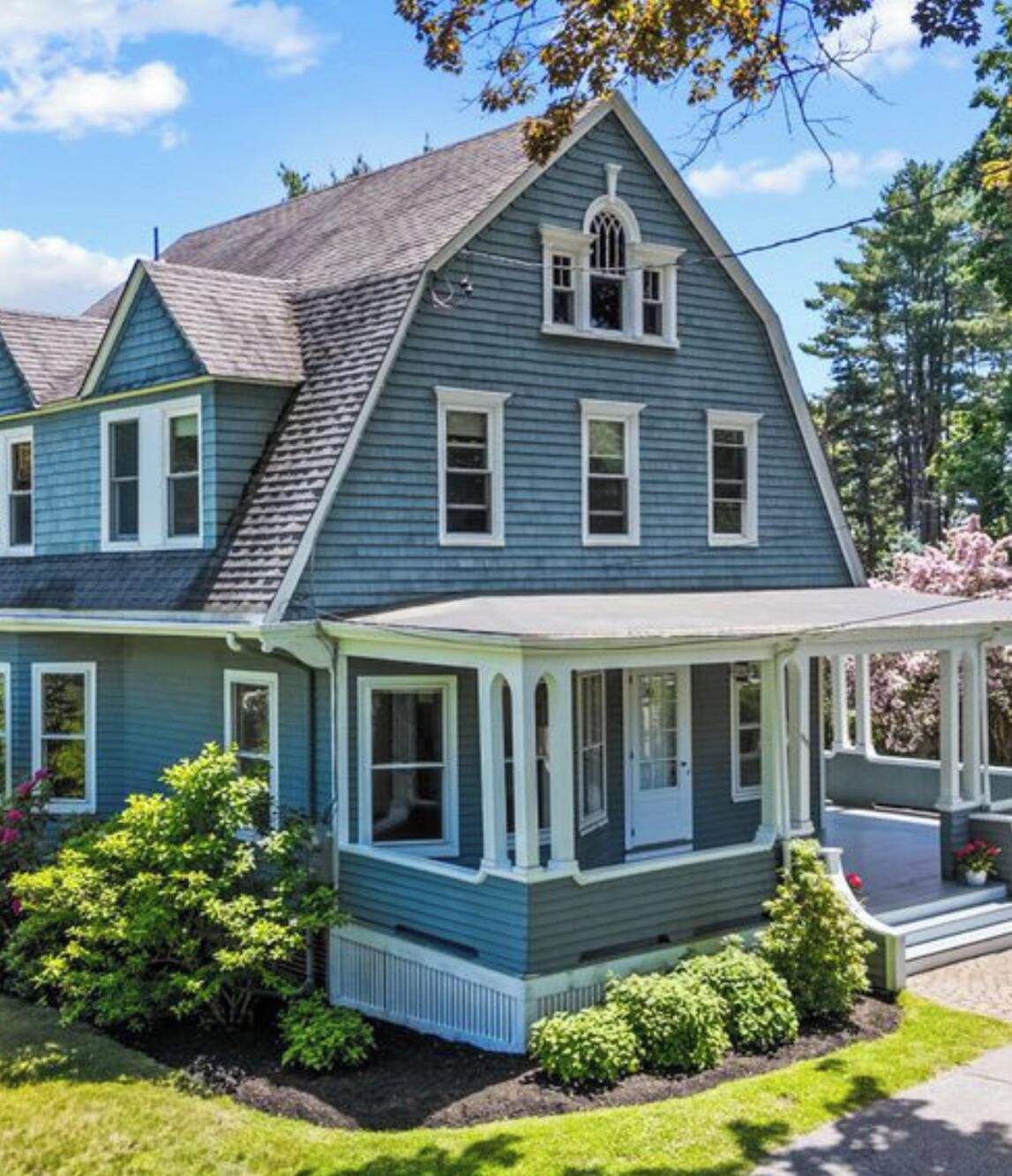 A two-story house with a wrap-around porch and a gabled roof.