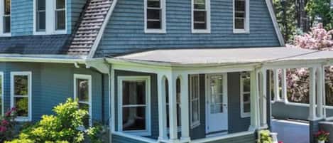 A two-story house with a wrap-around porch and a gabled roof.
