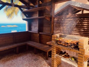Ein Sitzbereich im Freien mit Holzböden und einem Grill aus Ziegelsteinen zum Kochen.