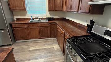 Una cocina con armarios de madera, una estufa de acero inoxidable y una ventana con persianas.