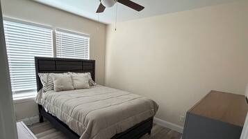 A bedroom with a bed, a ceiling fan, and a dresser.