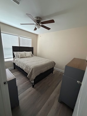 Ein Schlafzimmer mit einem Bett, einem Deckenventilator und einer Kommode.