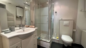 A modern bathroom with a glass shower enclosure, a white sink, and a toilet. - Cozy  Flat - La Fayette / Grands Boulevards (Paris)