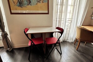 Zona de menjador amb taula i cadires, un quadre a la paret i una finestra amb cortines.