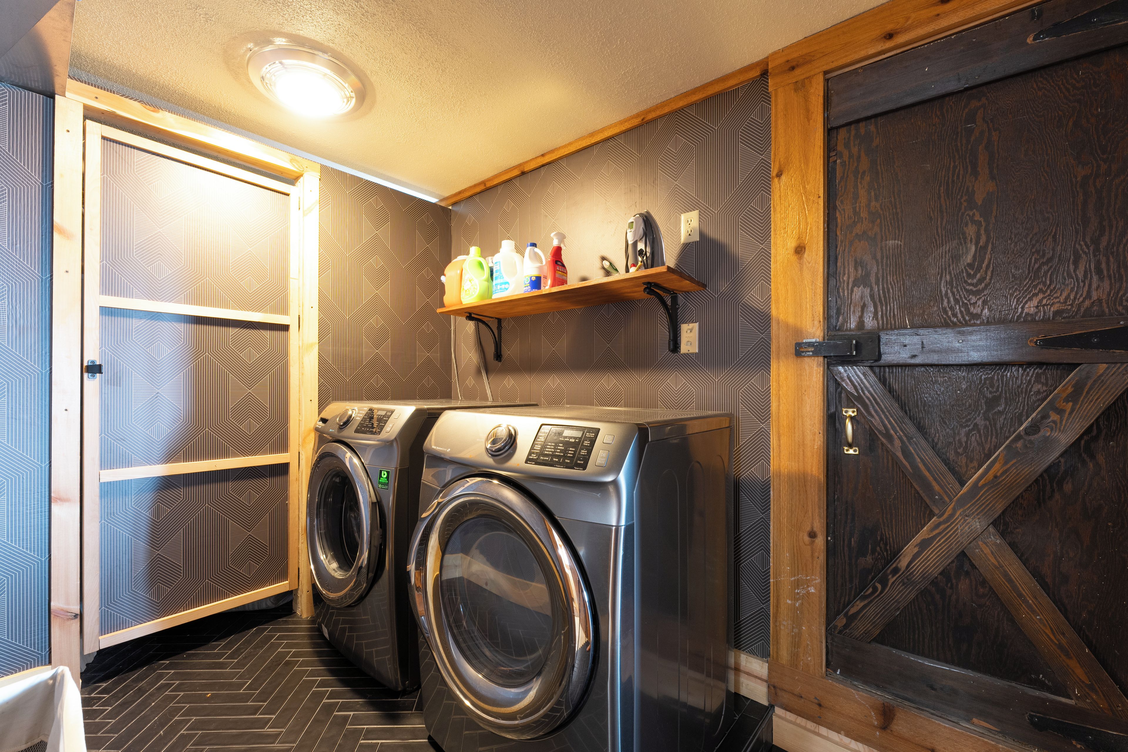 A laundry room with a washing machine, a drying rack, and a shelf with cleaning supplies.