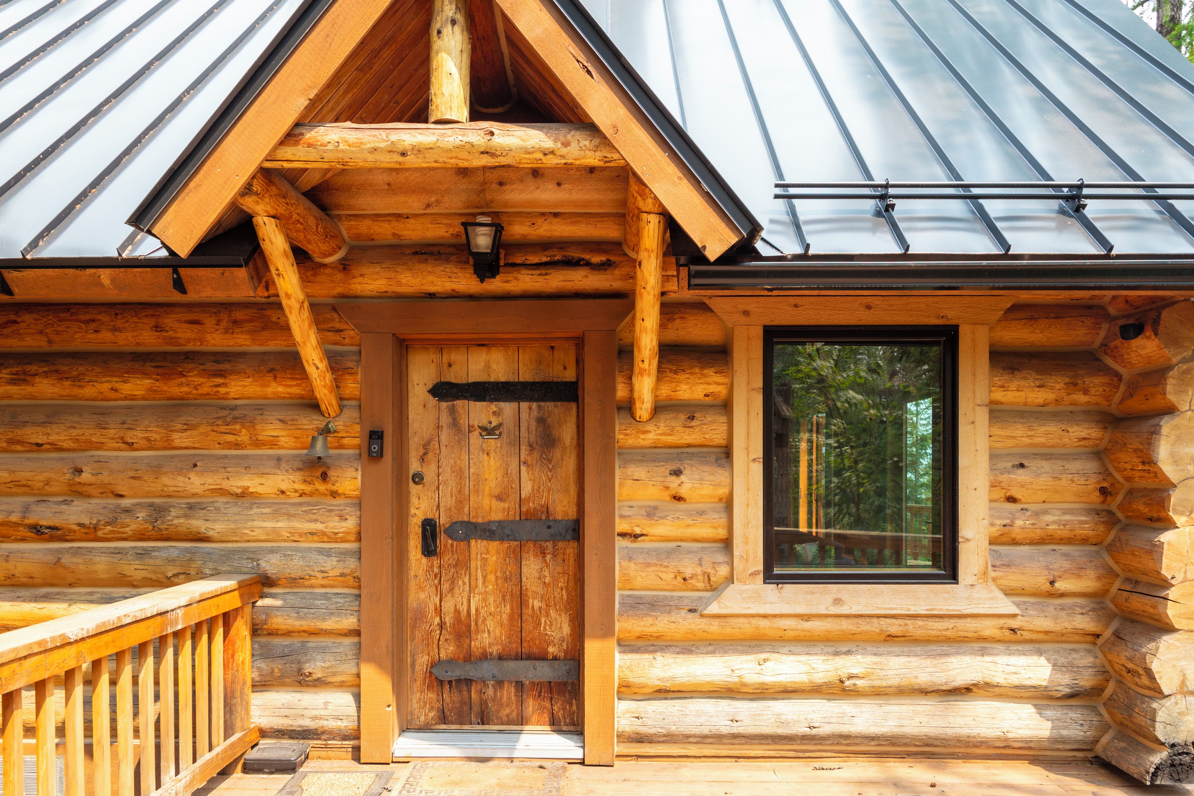 A log cabin with a wooden door, a window, and a metal roof.