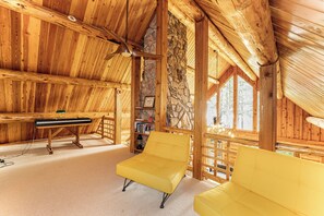 A cozy wooden interior with a piano, yellow sofas, and a stone wall.