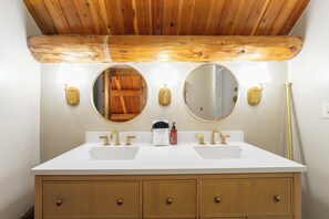 A bathroom with two sinks, wooden cabinets, and a wooden ceiling.