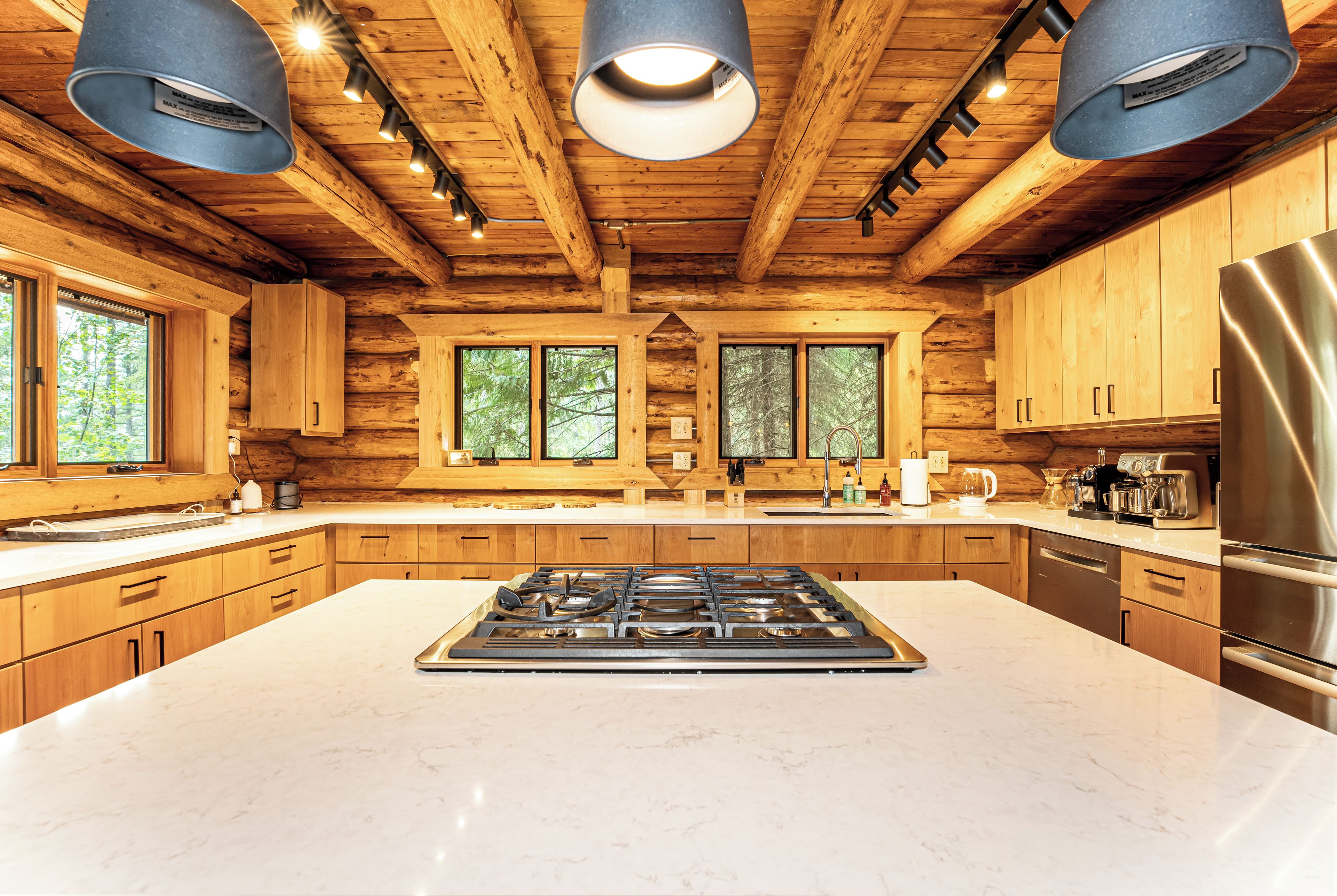 A spacious kitchen with a central island, wooden cabinetry, and a stainless steel refrigerator.