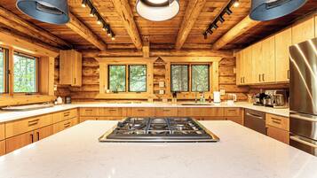 A spacious kitchen with a central island, wooden cabinetry, and a stainless steel refrigerator.