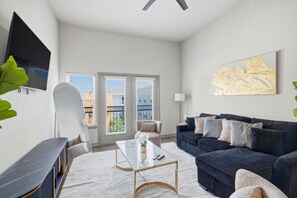 Ein modernes Wohnzimmer mit einer Couch, einem Couchtisch und einem an der Wand montierten Fernseher.