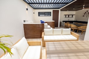A modern interior with a wooden bench, a white sofa, a dining area with wicker chairs, and a kitchen with a black countertop. - Fabulous Modern Luxury and Sophistication Penthouse, Temozon Norte (Merida)