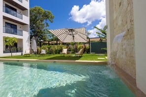 A swimming pool with clear water, surrounded by lounge chairs and a covered seating area with a striped canopy. - Fabulous Modern Luxury and Sophistication Penthouse, Temozon Norte (Merida)