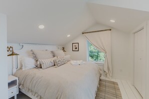 Ein Schlafzimmer mit einem Bett, einem Nachttisch und einem Fenster mit Vorhängen.