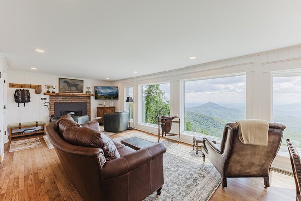 Ein geräumiges Wohnzimmer mit einer Ledersofa, einem Kamin und einem großen Fenster mit Blick auf die Berge.