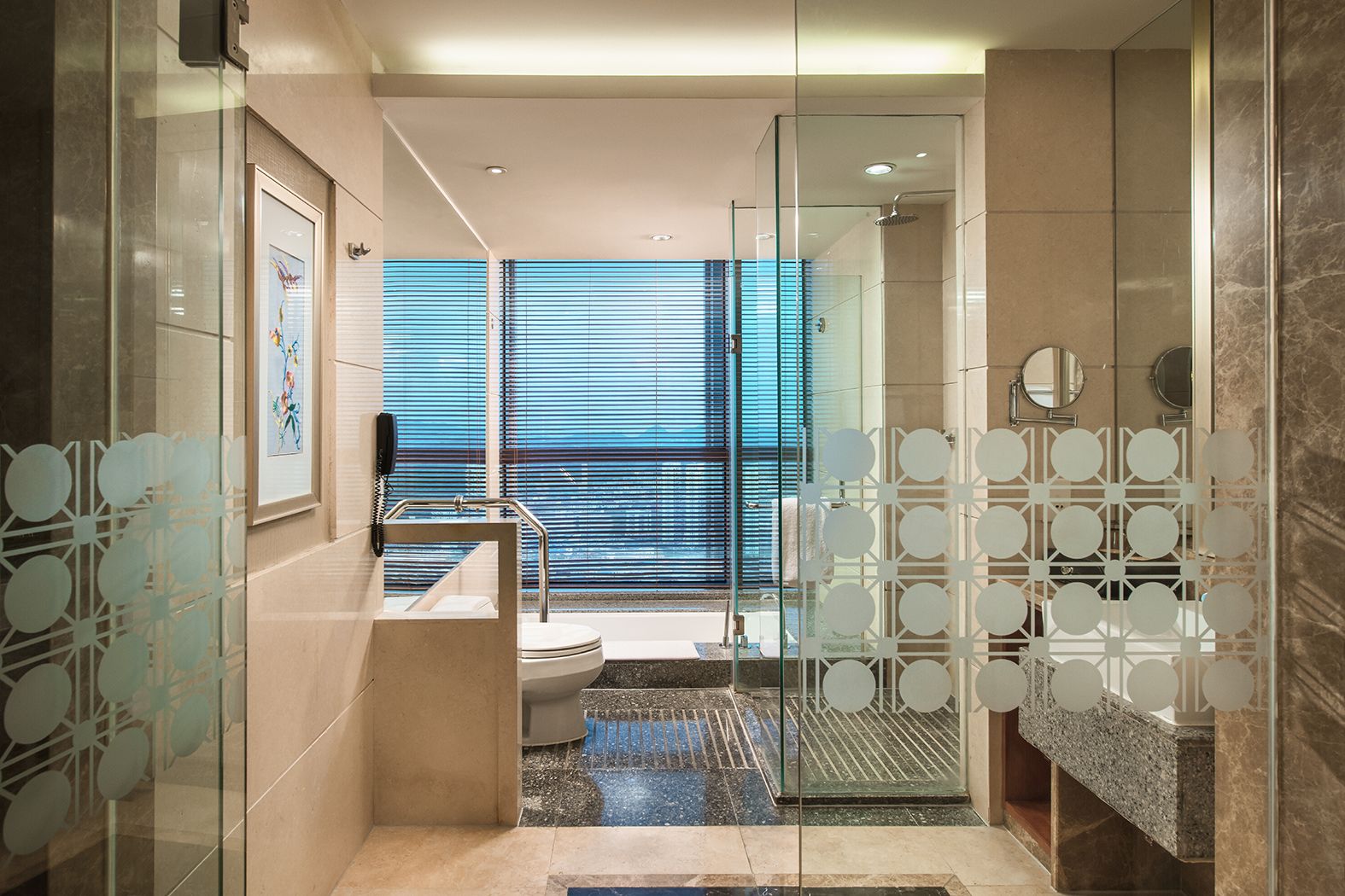 A modern bathroom with a glass shower enclosure, a toilet, and a sink with a decorative glass partition.