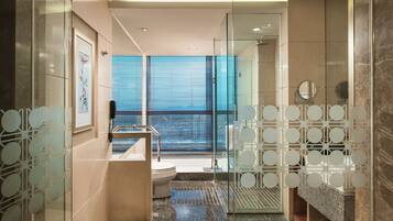 A modern bathroom with a glass shower enclosure, a toilet, and a sink with a decorative glass partition.