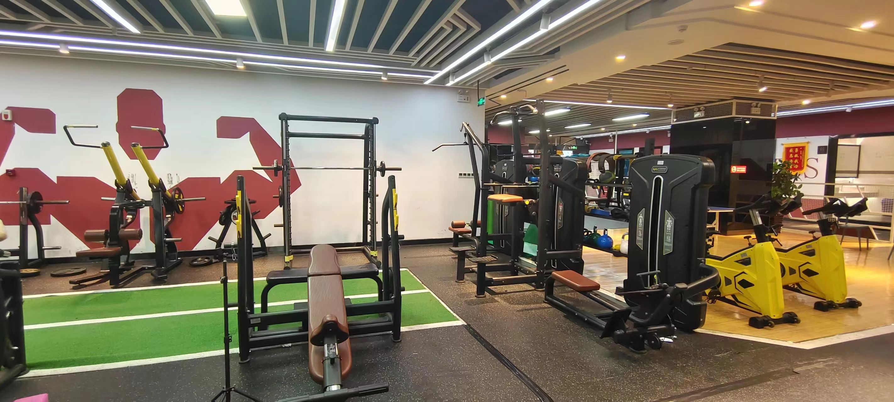 Une salle de sport équipée de divers appareils d’entraînement, notamment des machines à poids et des poids libres.