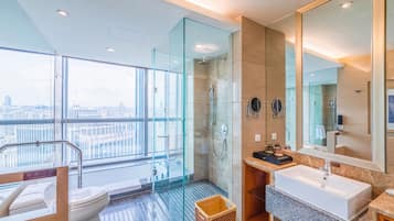 Un baño moderno con ducha de vidrio, un espejo grande y vistas a la ciudad.