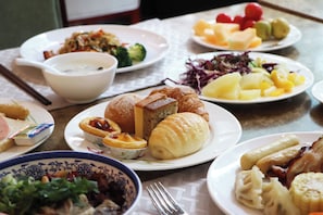 Una mesa dispuesta con diferentes platos, incluyendo pan, un tazón de sopa y una fuente de fruta.