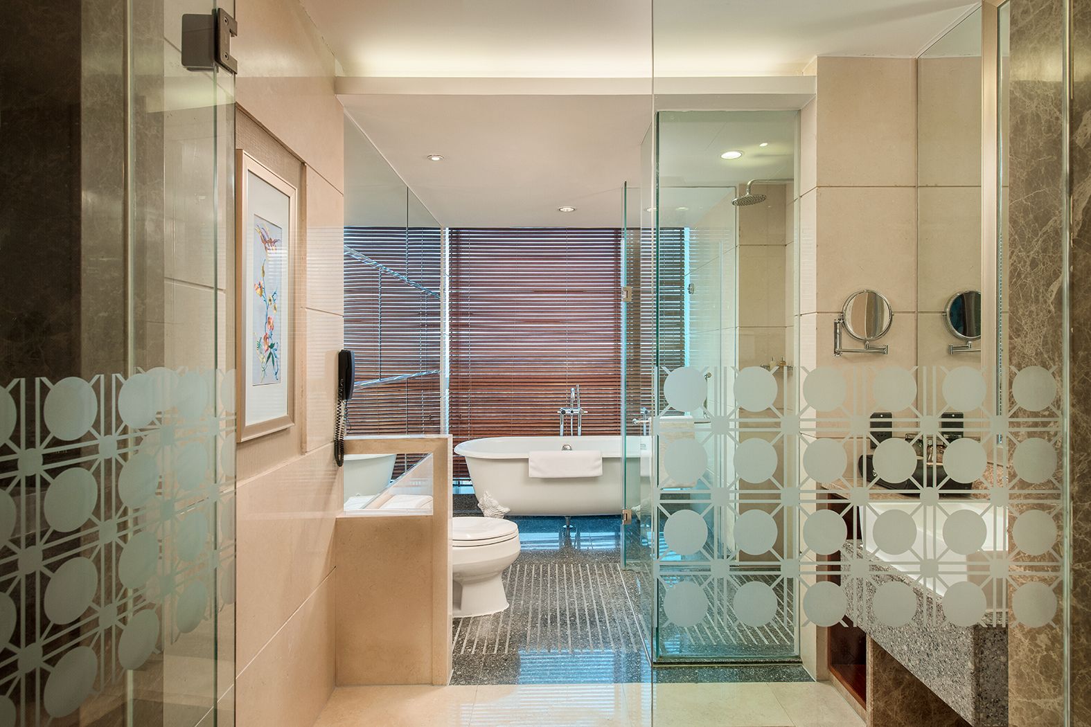 Ein modernes Badezimmer mit Glastrennwand, Badewanne, Toilette und Waschbecken.