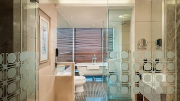 Ein modernes Badezimmer mit Glastrennwand, Badewanne, Toilette und Waschbecken.